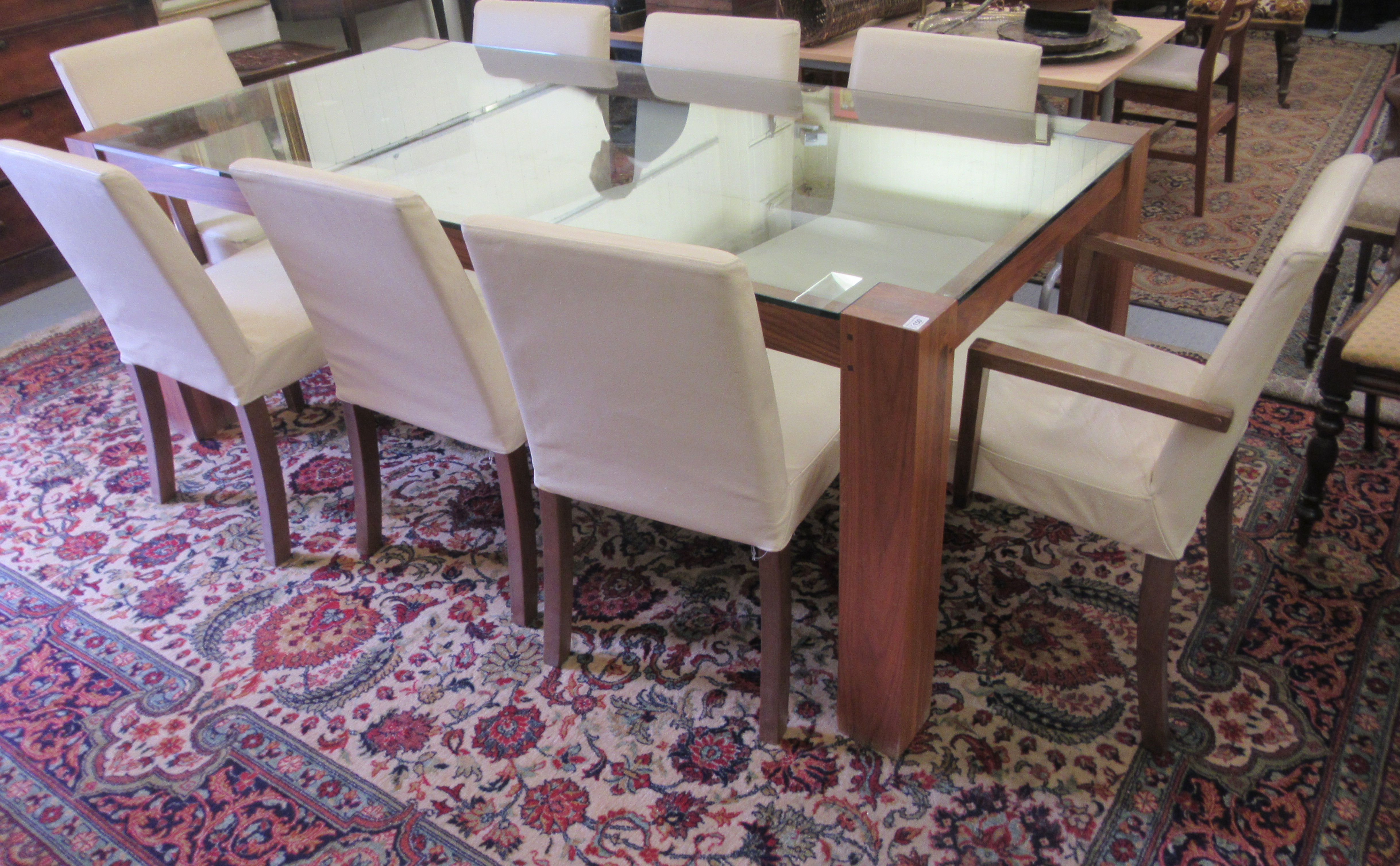 A modern dining table, the glass top raised on a teak underframe, raised on square, block legs  30'h