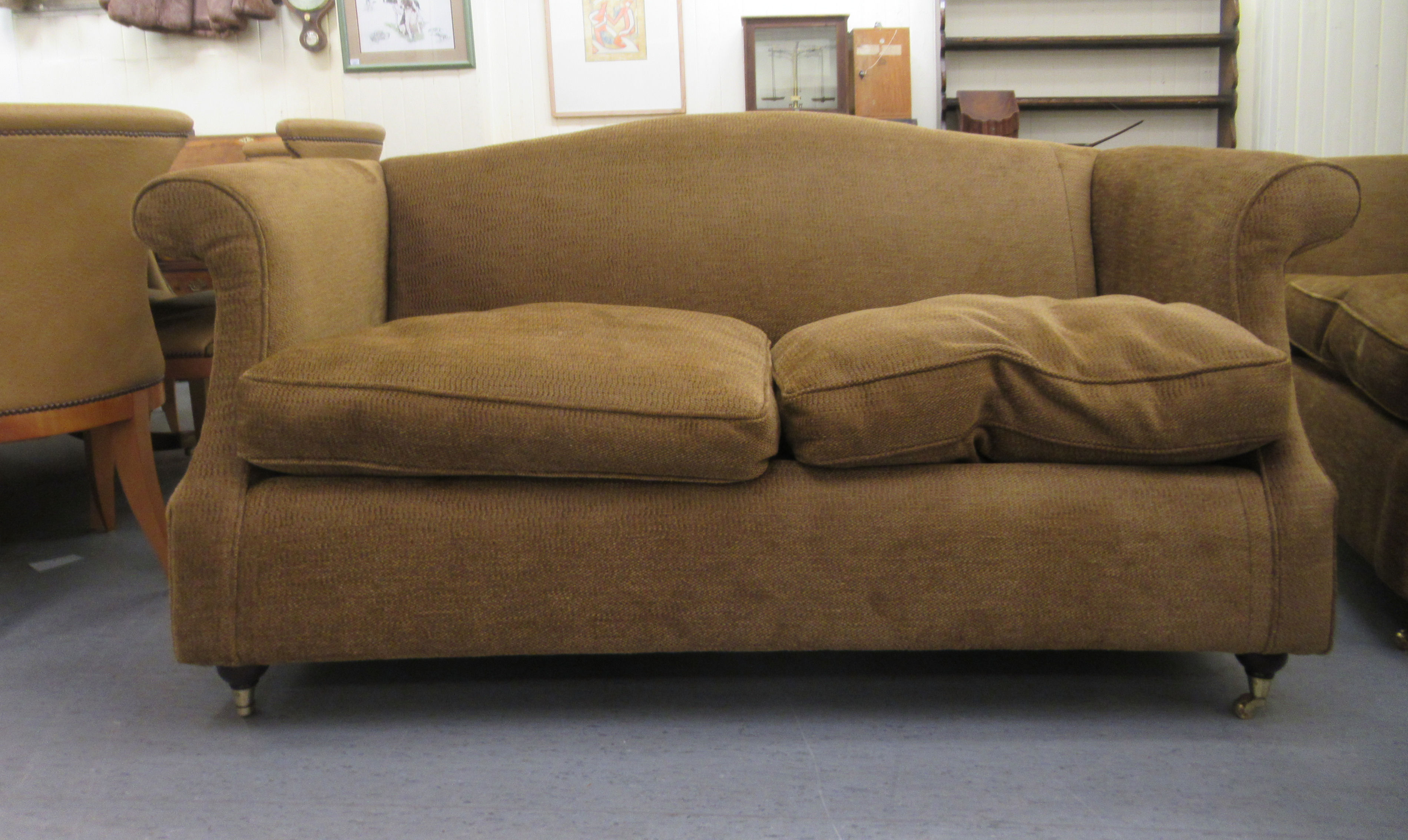 A modern textured fabric upholstered two person settee with an arched back and level arms, raised on