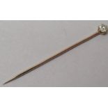 A gold coloured metal stick pin, claw set with a diamond