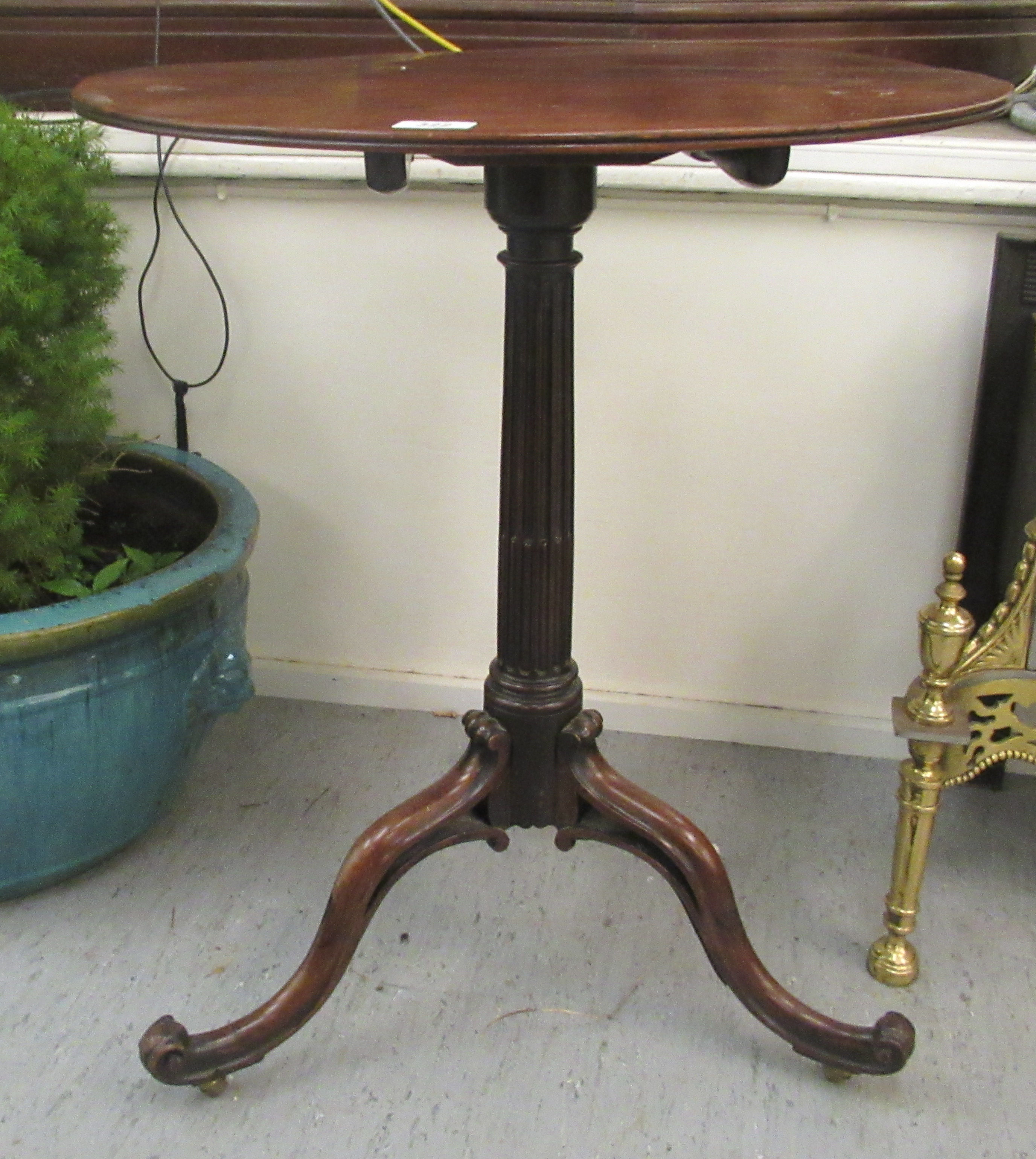 A Regency mahogany pedestal table, the tip-top over a fluted and reeded column, raised on scrolled