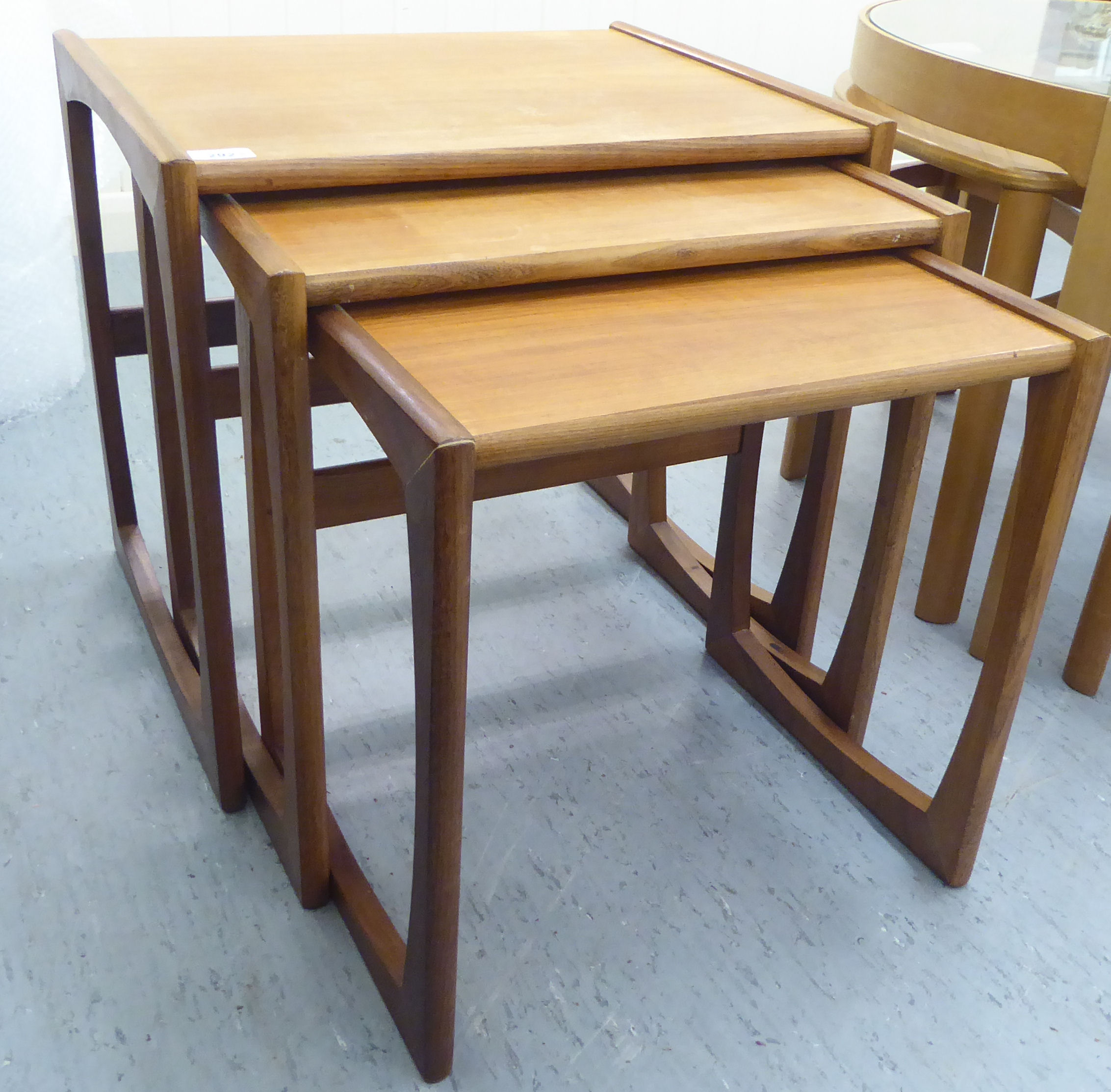 A nesting set three 1970s teak occasional tables, raised on splayed end supports  largest 19"h  21"w