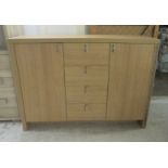 A modern light oak sideboard with a central bank of four drawers, flanked by a pair of cupboard