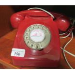 A telephone handset in pillar box red plastic casing with cradle receiver and rotating dial