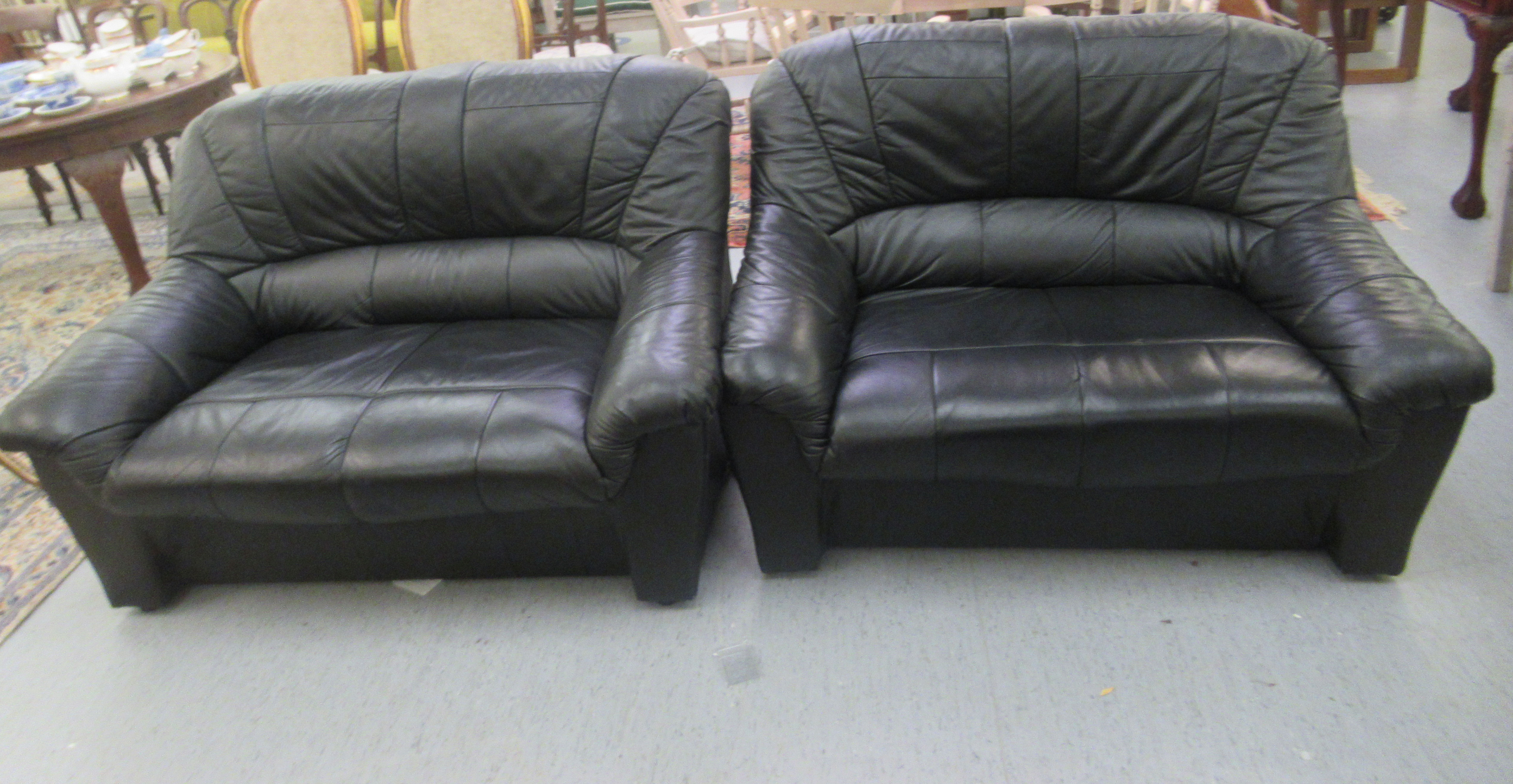 A pair of modern stitched black hide upholstered two person settees  52"w