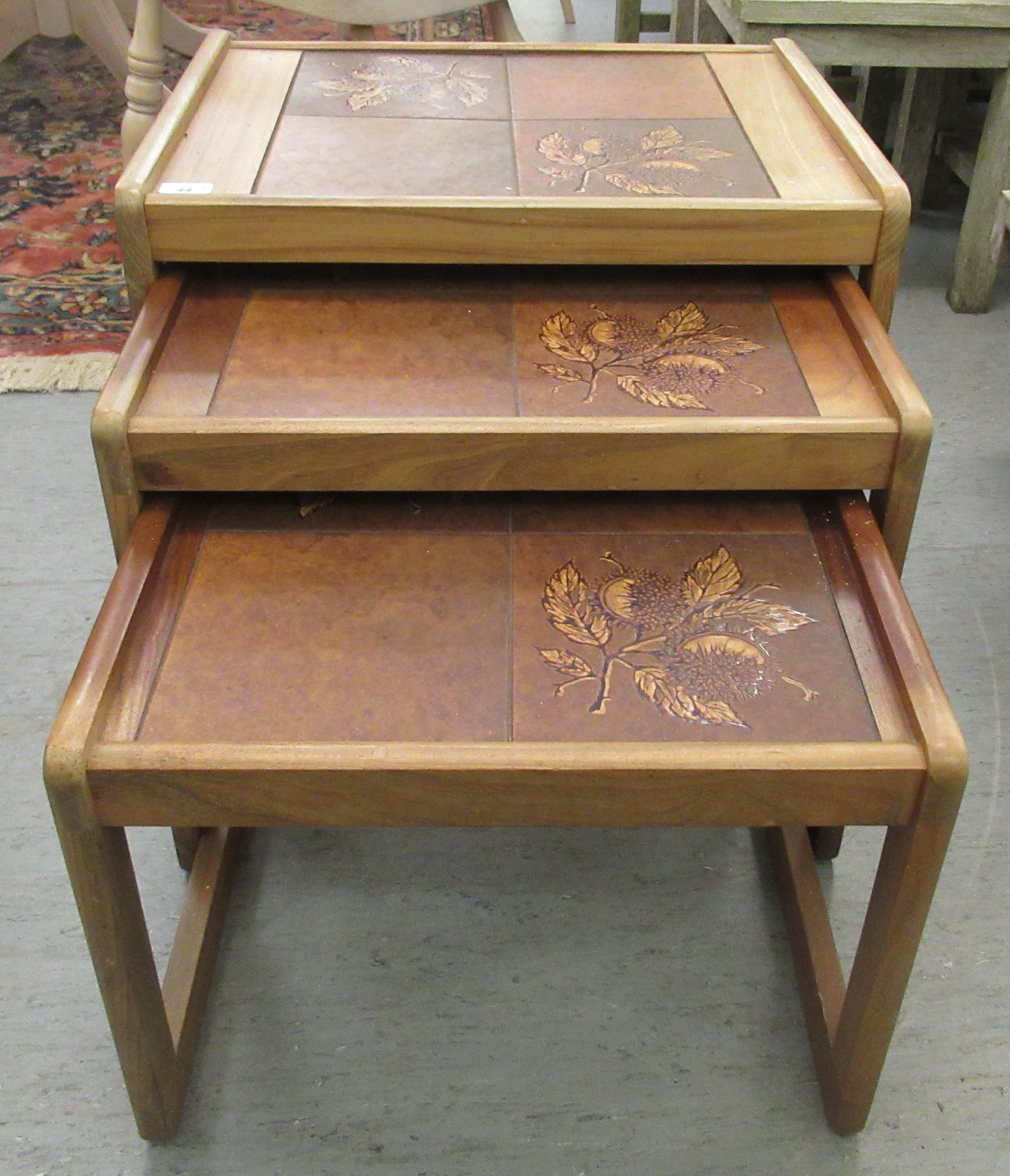 A nesting set of three modern teak framed tile top occasional tables, raised on block legs