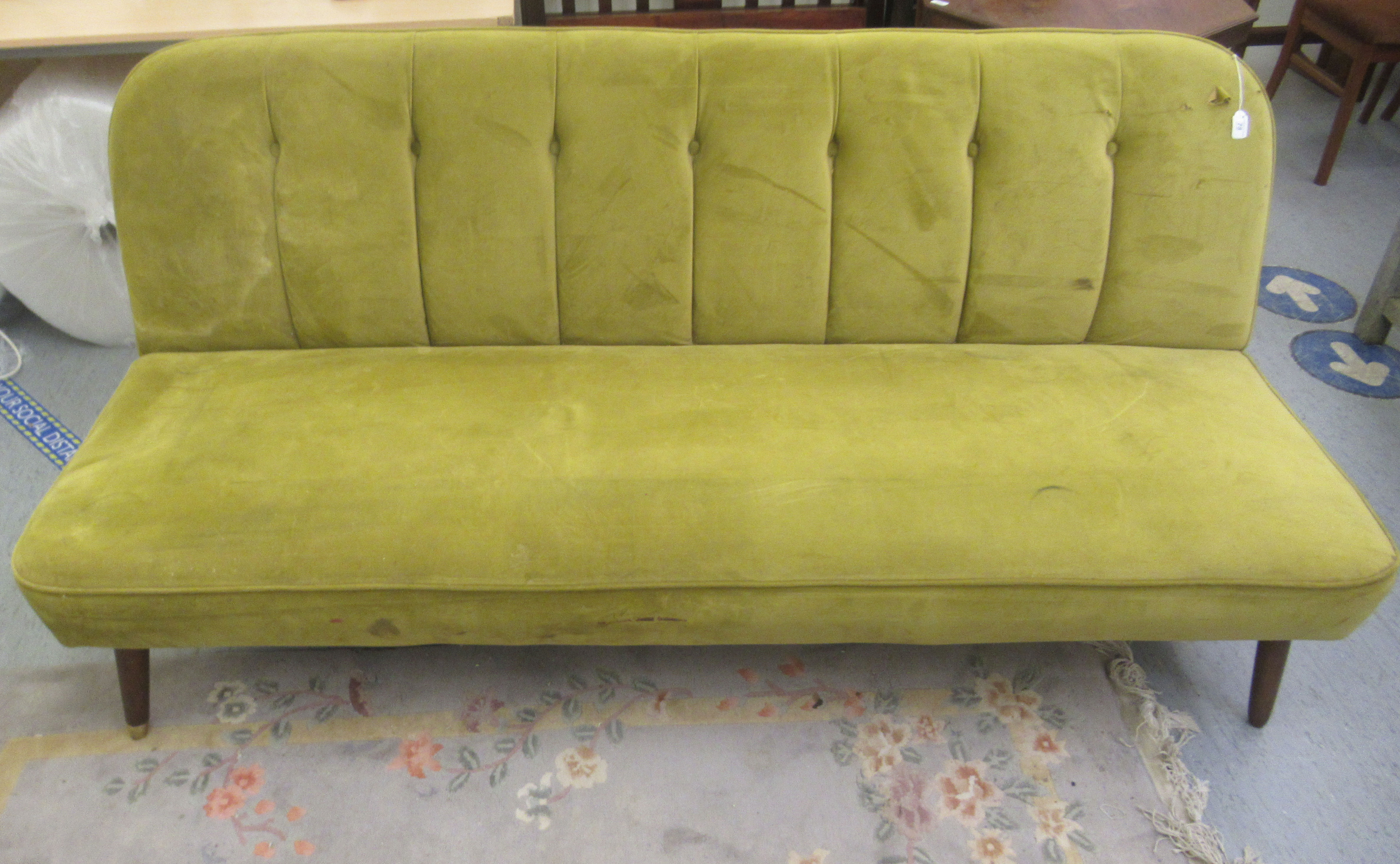 A vintage style lime green button upholstered four person settee, raised on teak tapered legs