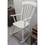 A cream painted bar and lath back open arm rocking chair