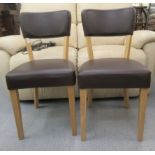 A pair of Ikea light oak framed dining chairs with black vinyl upholstered cushioned backs and