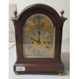 An Edwardian mahogany cased bracket clock with a round arched top, brass finials, canted and stop