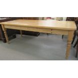 A 20thC pine farmhouse kitchen table, the planked top with rounded corners, raised on block, turned,