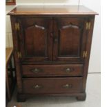 A 20thC Old English style oak cabinet with a pair of panelled doors, over two drawers, raised on