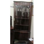 A modern mahogany finished serpentine front corner cabinet with an astragal glazed dorr and