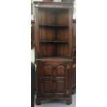 A 20thC oak Old English style oak two part corner cabinet, the upper section with two open