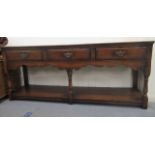 A 20thC Old English style oak three drawer sideboard, raised on turned and block forelegs, united by