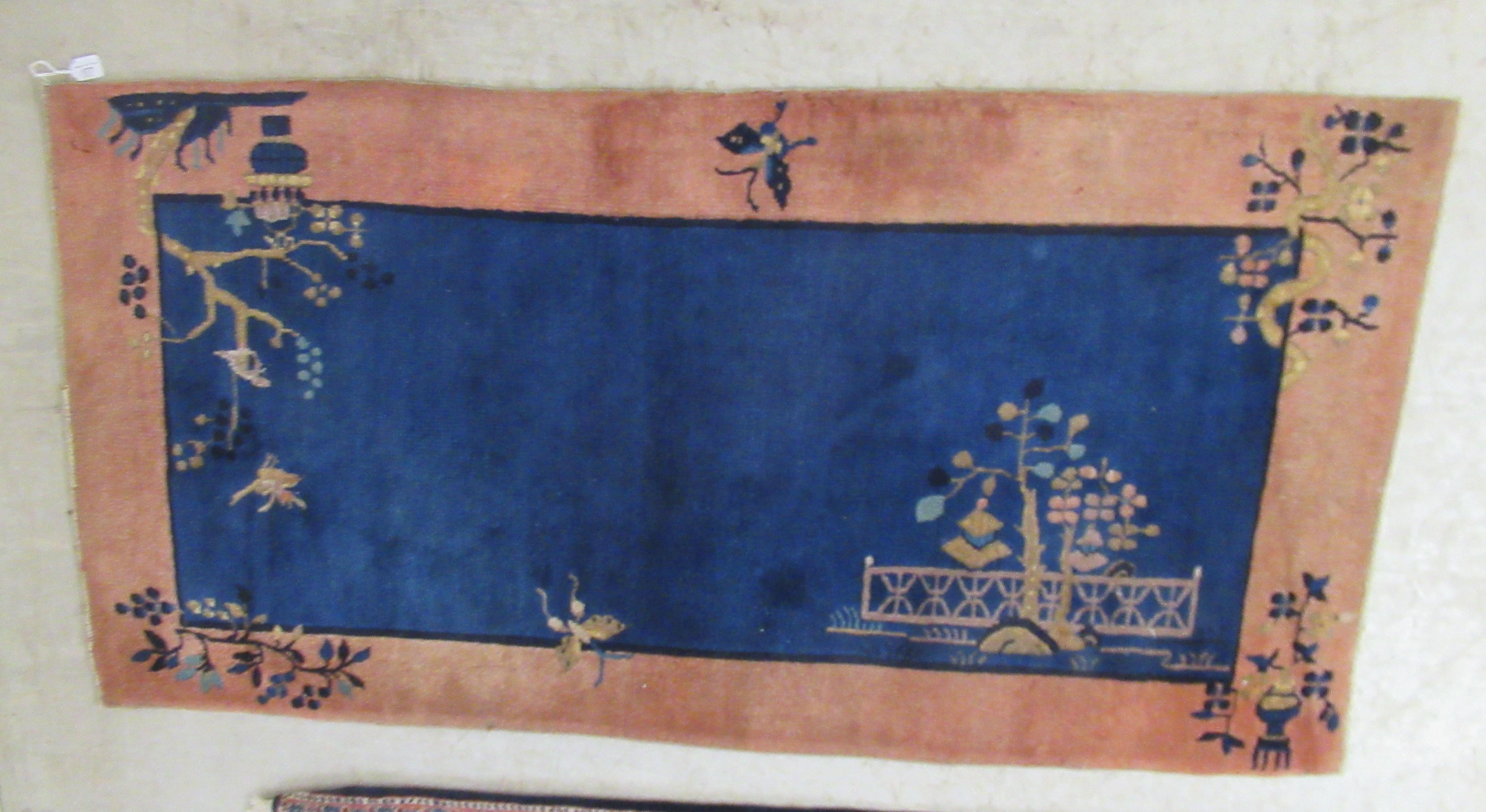 A Chinese Export woollen rug, circa 1950, decorated with a landscape on a mainly blue coloured
