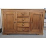 An early 20thC stained pine dresser base with four central drawers, flanked by two cupboard doors,