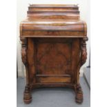 A mid Victorian walnut veneered piano top Davenport, comprising a rising lid with a brown hide