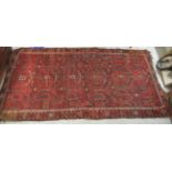 A Turkoman rug, decorated with repeating, stylised designs, on a red ground  97" x 50"