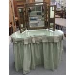 A modern peppermint green fabric covered kidney shape dressing table, raised on block legs  28"h