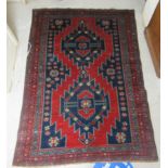 A Caucasian rug, decorated with two central diamond shaped motifs on a red and blue ground  61" x