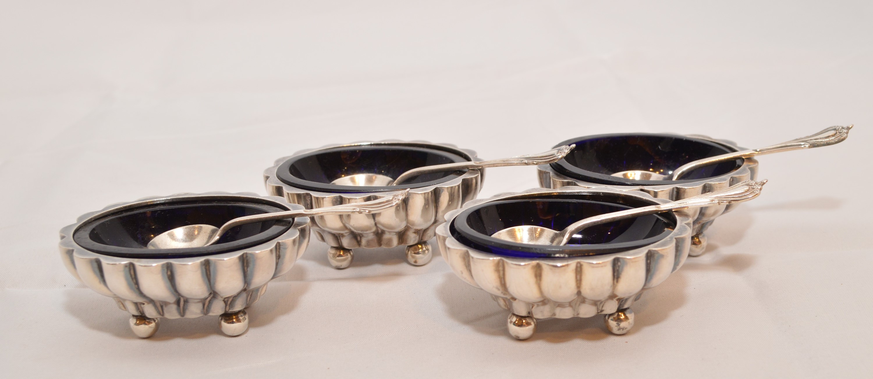 A set of four silver table salts and spoons