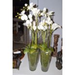 Imitation orchids and lilies in glass vases.