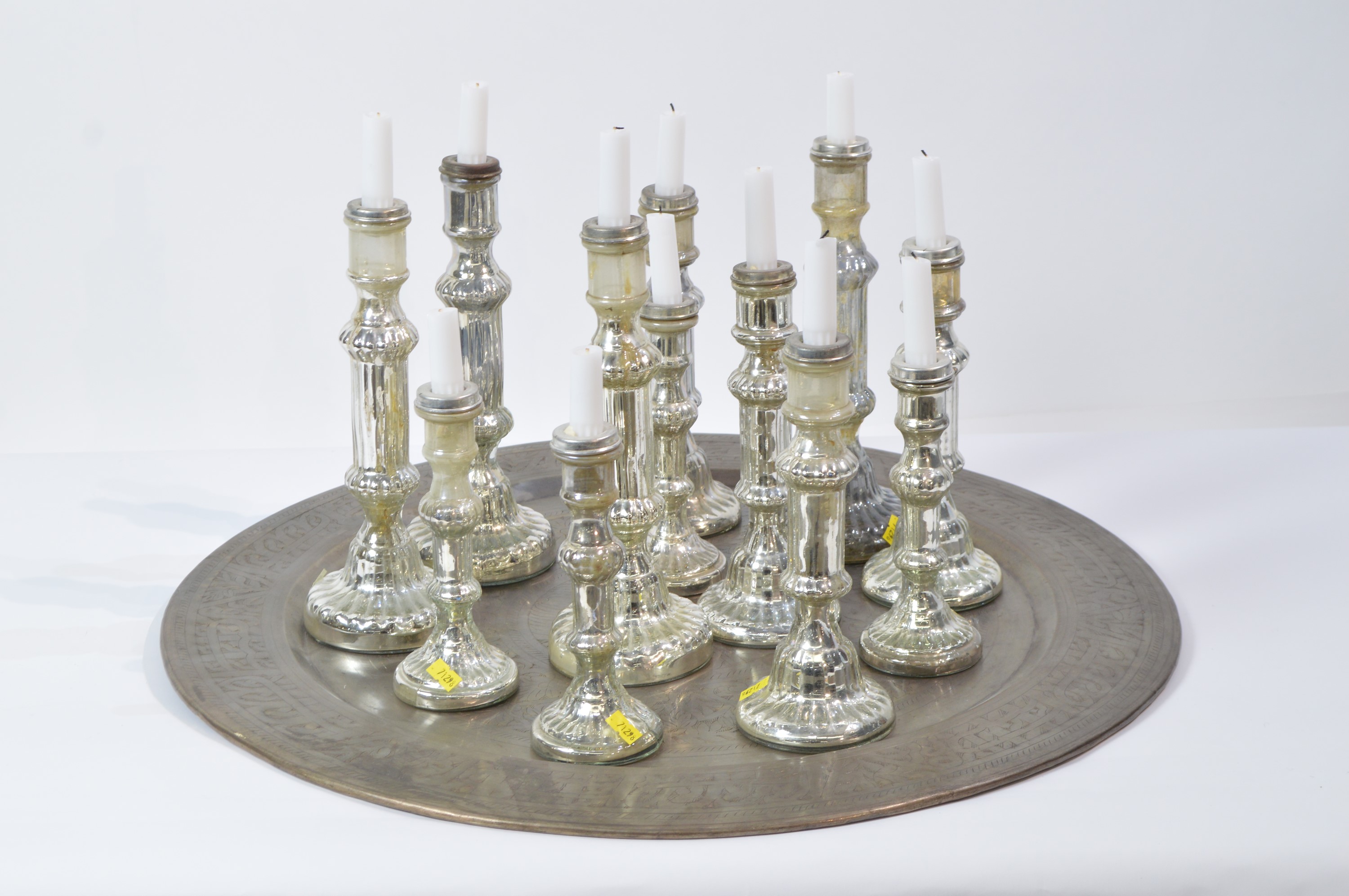 Twelve assorted candlesticks on Indian style tray.