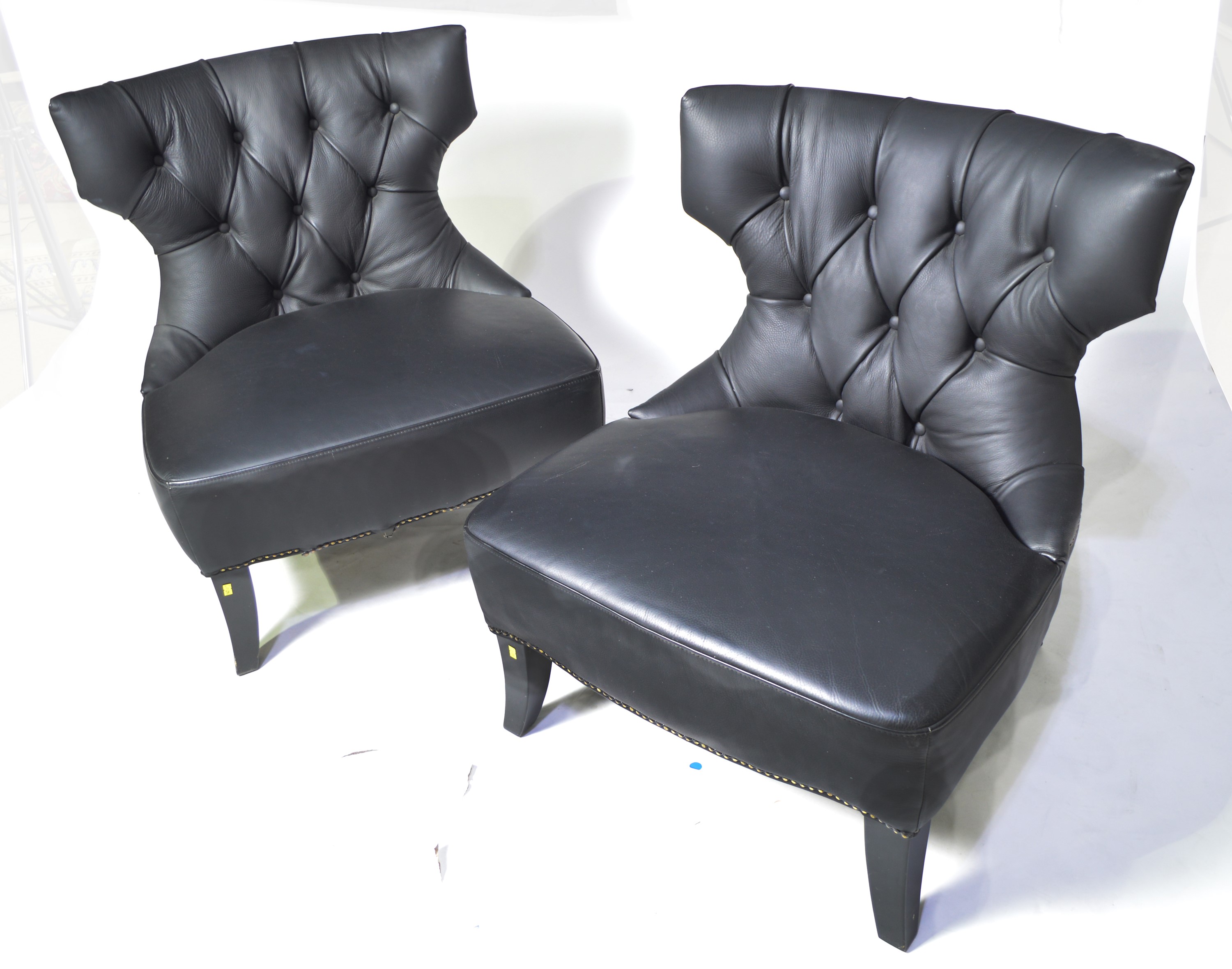 A pair of designer faux black leather easy chairs.