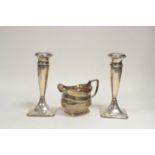 A pair of silver candlesticks; and a cream jug.