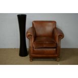 20th C brown leather armchair; and a black glass vase.