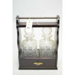 An Edwardian-style mahogany tantalus with two cut glass decanters.