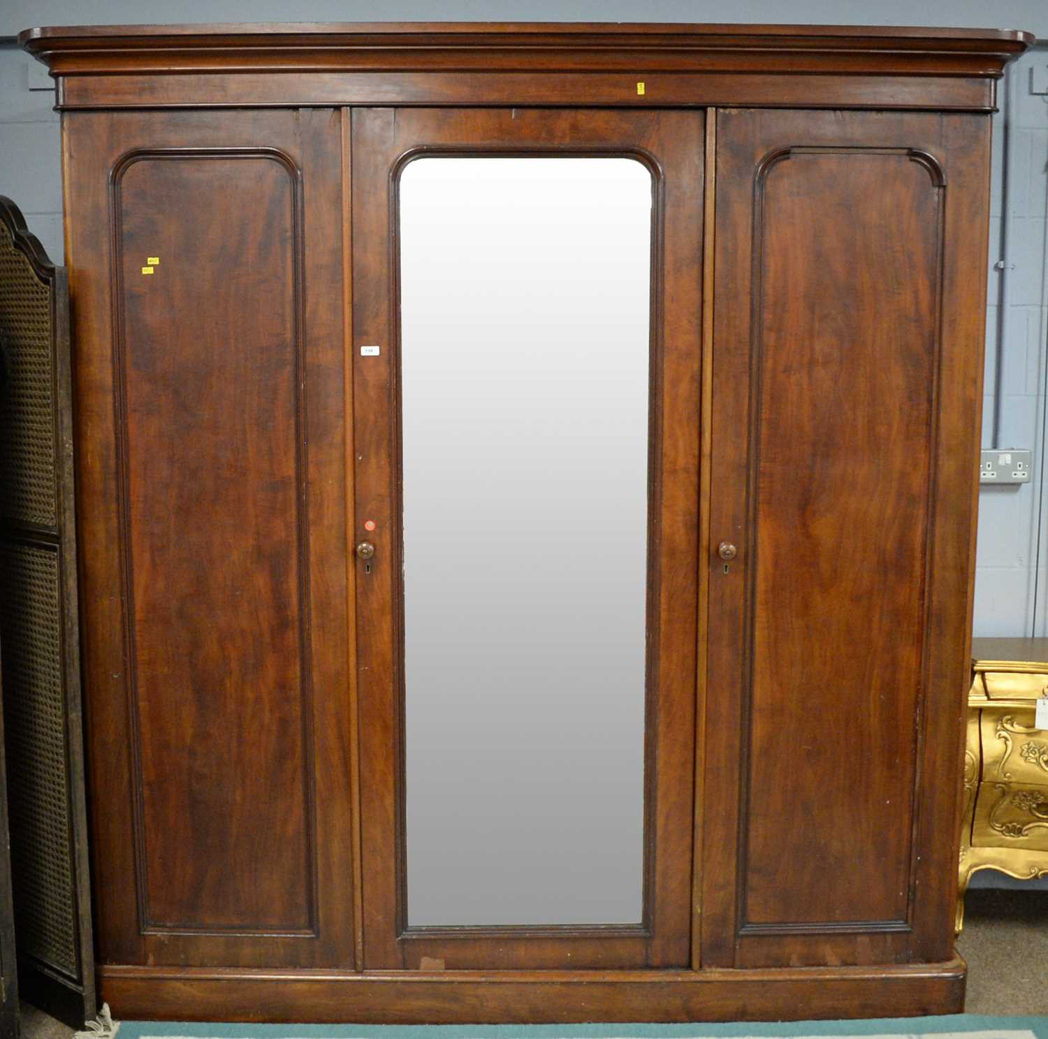 A Victorian mahogany three-door wardrobe, the projecting cornice above a central bevelled mirror