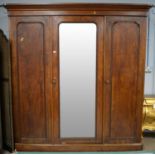A Victorian mahogany three-door wardrobe, the projecting cornice above a central bevelled mirror