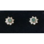 A pair of emerald and diamond cluster earrings.