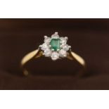 An emerald and diamond cluster ring.