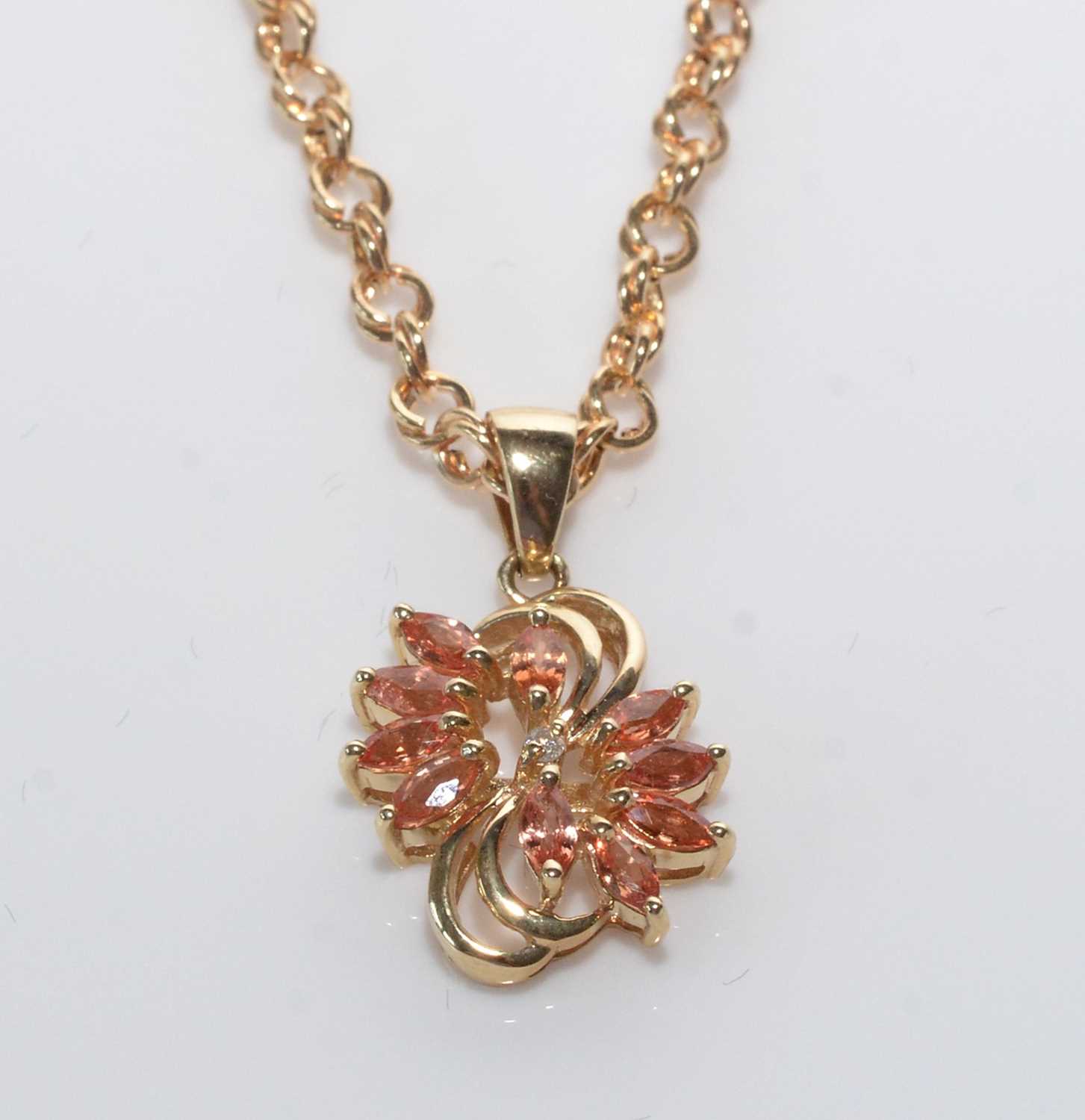 A peach coloured sapphire, diamond and 14ct. yellow gold pendant.