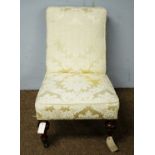 A Victorian nursing chair upholstered in gold damask style fabric
