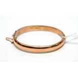 A 9ct gold hinged bangle.