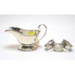 A George V silver sauce boat, by Walker and Hall, and three silver napkin rings.