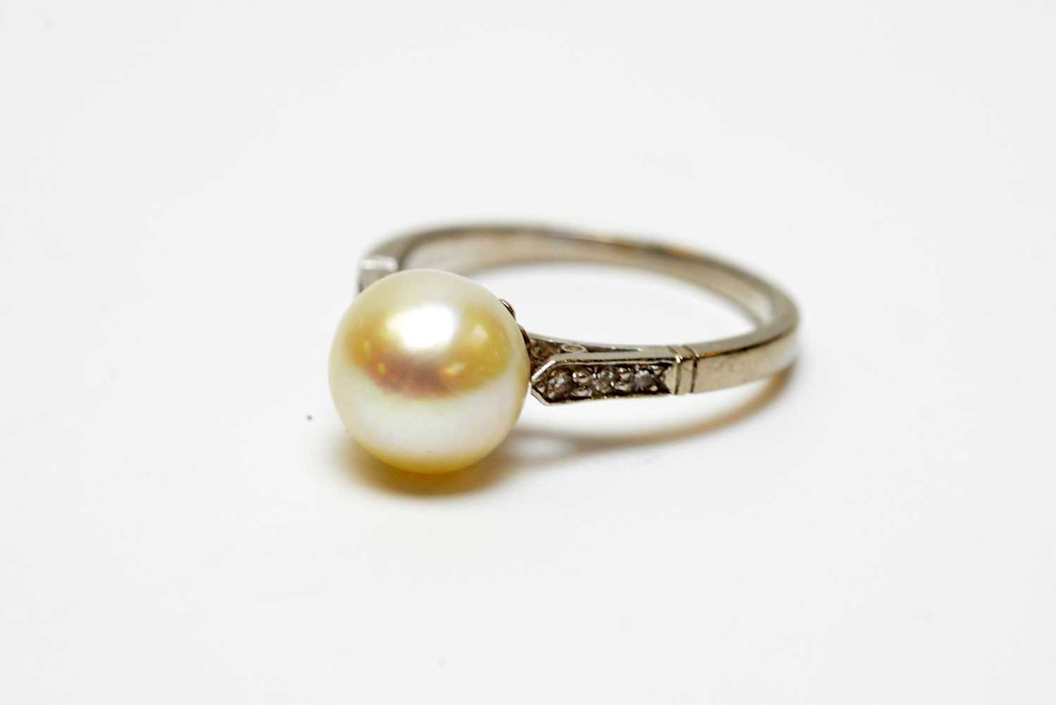 A high-carat white metal, diamond, and pearl solitaire cocktail ring.