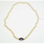 A pearl necklace with high-carat white metal, diamond, and sapphire clasp.