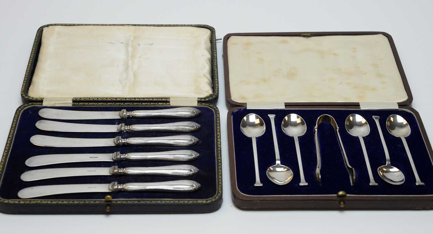 A cased set of six George V silver teaspoons and sugar tongs, and a cased set of butter knives.