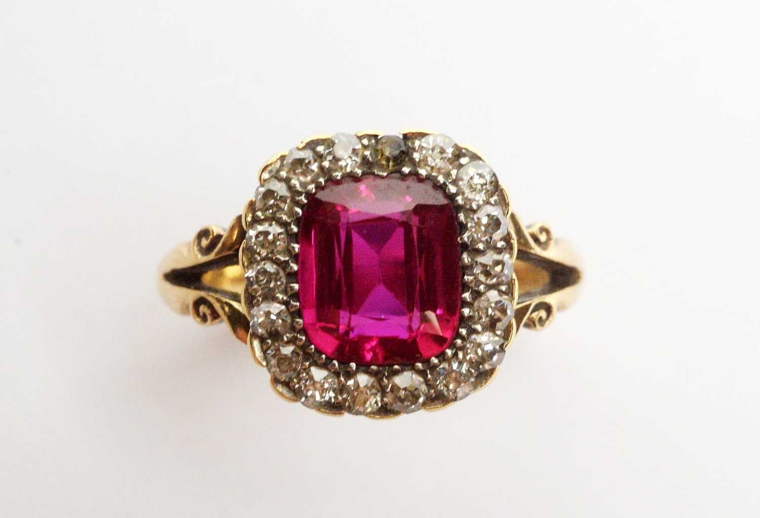 A yellow metal, diamond, and synthetic ruby ring.