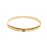 Yellow metal bangle bezel set with a single white stone.