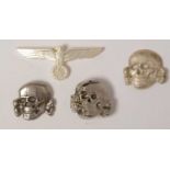 Three reproduction WWII SS Toten Kopf badges and a cap badge