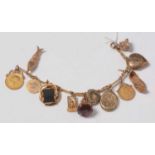 A yellow-metal charm bracelet suspended with an assortment of charms including sovereigns.