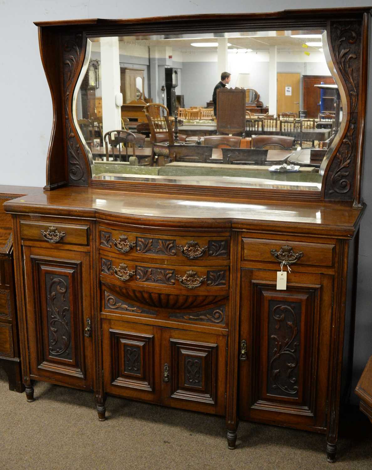 An Edwardian carved walnut bowfront mirror-back sideboard.