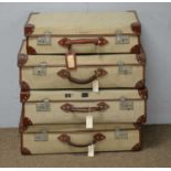 Four vintage canvas and leather-bound suitcases.