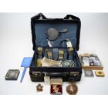 A fitted travel case containing a silver-backed dressing table set and other accoutrements.