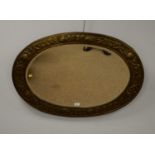 An ornate embossed brass oval mirror